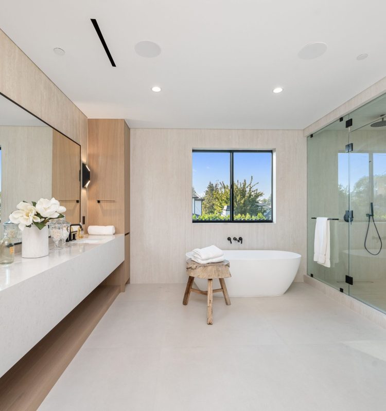 Modern luxury bathroom with a sleek minimalist design, featuring a freestanding tub, glass shower, and large vanity with elegant decor.